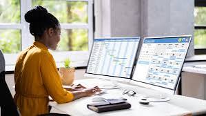 "Front desk coordinator reviewing an appointment schedule on a dual-monitor setup" 